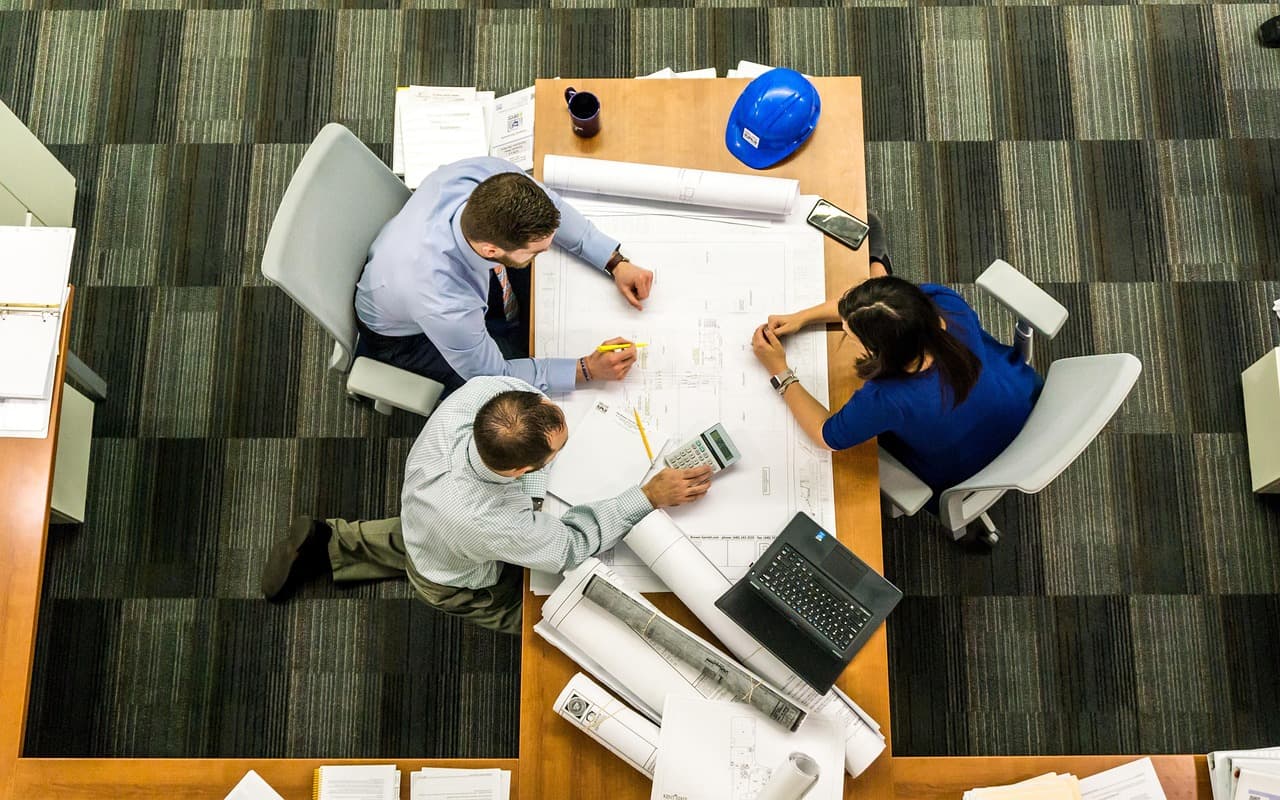 People gathered around a table, working through plans and figures together